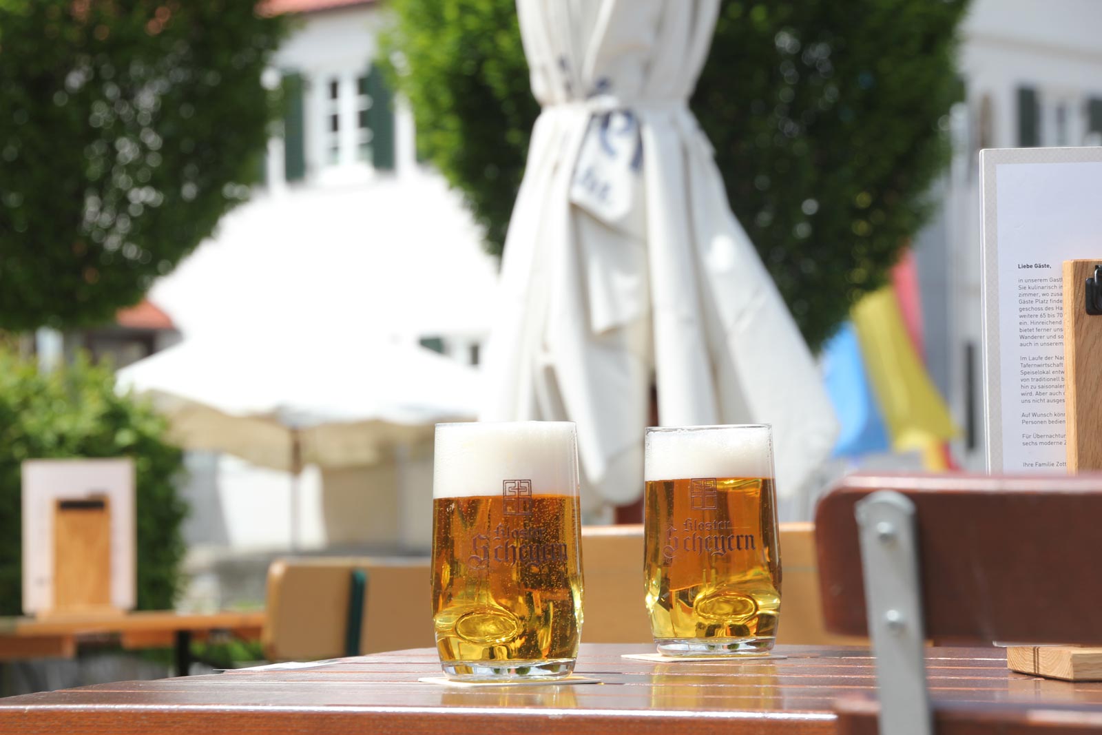 zwei gefüllte Bierkrüge stehen auf einem Tisch auf einer sonnigen Terrasse